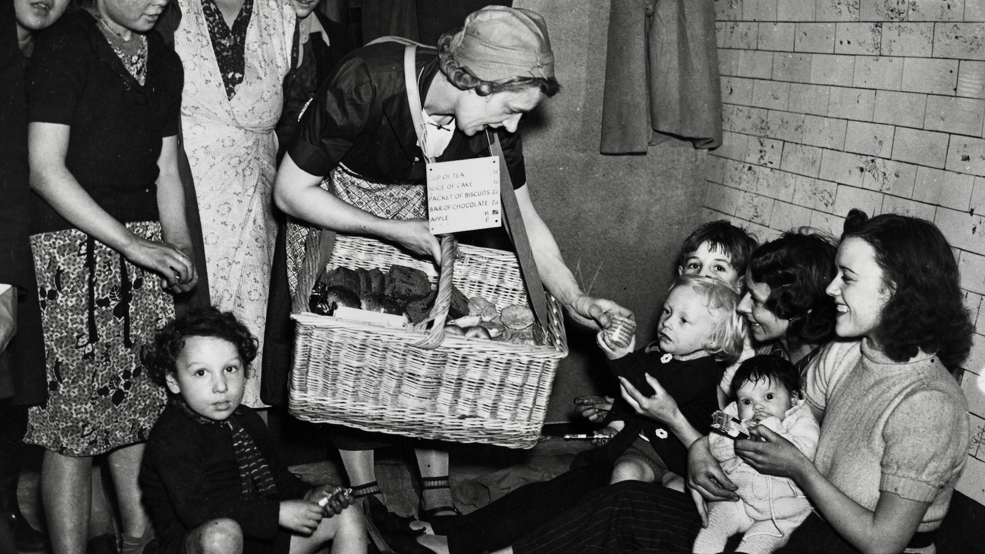 A woman selling biscuits to people using an underground tube station as an air raid shelter, U.K., January 1, 1940. Photo by Fox Photos/Getty Images