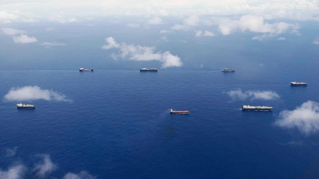 Various US Navy at-sea-replenishment and sealift ships sail in formation.