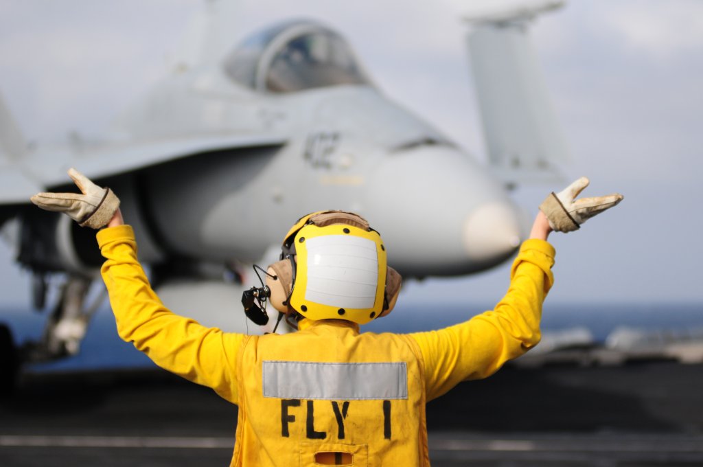 Aviation Boatswain's Mate (Handling) 3rd Class Alexis Lebrake, assigned to the air department aboard the aircraft carrier USS Carl Vinson (CVN 70), guides an F/A-18C Hornet as it taxis on the flight deck. Carl Vinson and Carrier Air Wing (CVW) 17 are underway on a deployment to the western Pacific region.