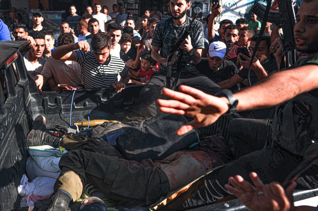EDITORS NOTE: Graphic content / Palestinians surround a truck reportedly carrying two dead Israeli soldiers in its back , in Khan Yunis in the southern Gaza Strip, on October 7, 2023. One month after Israel was wracked by Hamas attacks, life has been upended for both the Palestinians and Israel after it launched a war of reprisal in the Gaza Strip. The October 7 attacks by Hamas militants who stormed across from Gaza and struck kibbutzim and southern Israeli areas killed 1,400 people, mostly civilians, and deeply scarred the nation. The health ministry in Hamas-run Gaza says nearly 9,500 have been killed, two-thirds of them women and children, and mostly civilians. (Photo by AFP) (Photo by -/AFP via Getty Images)