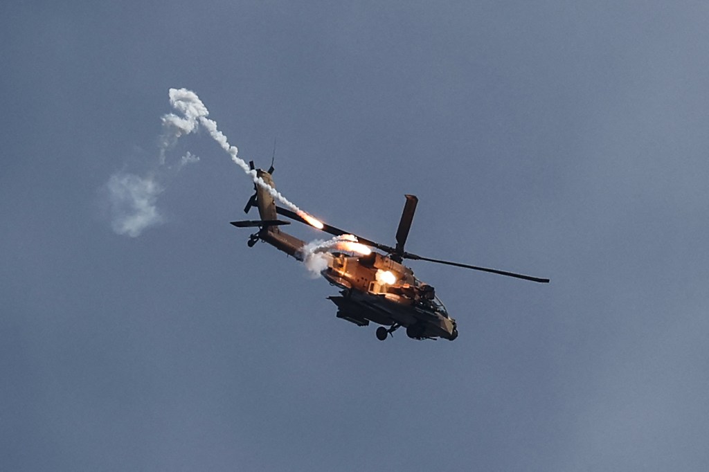 This picture taken from southern Israel near the border with the Gaza Strip on December 8, 2023, shows an Israeli army helicopter firing on a target in northern Gaza, amid continuing battles between Israel and the militant group Hamas. (Photo by JACK GUEZ / AFP) (Photo by JACK GUEZ/AFP via Getty Images)