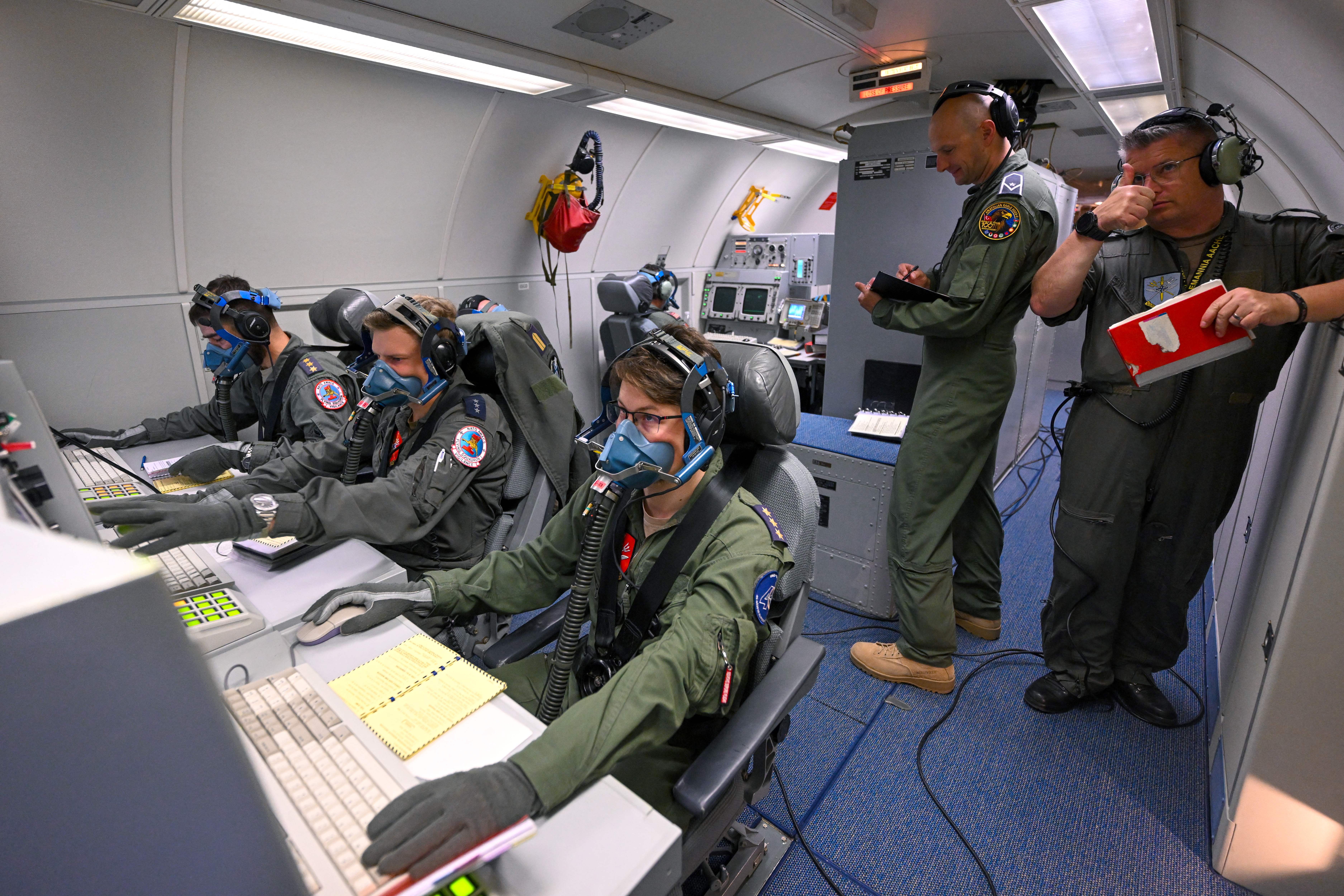 Operators wear oxygen masks as they work during an emergency exercise in a NATO Airborne Warning and Control System (AWACS) aircraft, which participates in the German-led multinational exercise Air Defender 23, during a flight over northern Germany from the military base of Geilenkirchen, western Germany, on June 20, 2023. NATO AWACS enables the exercise by providing airborne command and control with its long-range radar and passive sensors for the participating fighter aircraft. Air Defender 23 is the largest air force deployment exercise in NATO's history. Under the lead of the German air force, about 10,000 troops from Allied and Partner nations practice a fictitious collective defence scenario, in which Allies and Partners deploy their forces to Germany to defend NATO territory with swift and decisive action. (Photo by Ina FASSBENDER / AFP) (Photo by INA FASSBENDER/AFP via Getty Images)