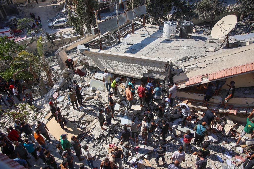 People and emergency crews look for survivors following Israeli bombardment on the Al-Nassr school that houses displaced Palestinians, West of Gaza City, on August 4, 2024, amid the ongoing conflict between Israel and the militant Hamas group. Gaza's civil defence agency said an Israeli strike hit two schools in Gaza City on August 4, killing at least 30 people, while the Israeli army reported it had struck Hamas command centres. (Photo by Omar AL-QATTAA / AFP) (Photo by OMAR AL-QATTAA/AFP via Getty Images)