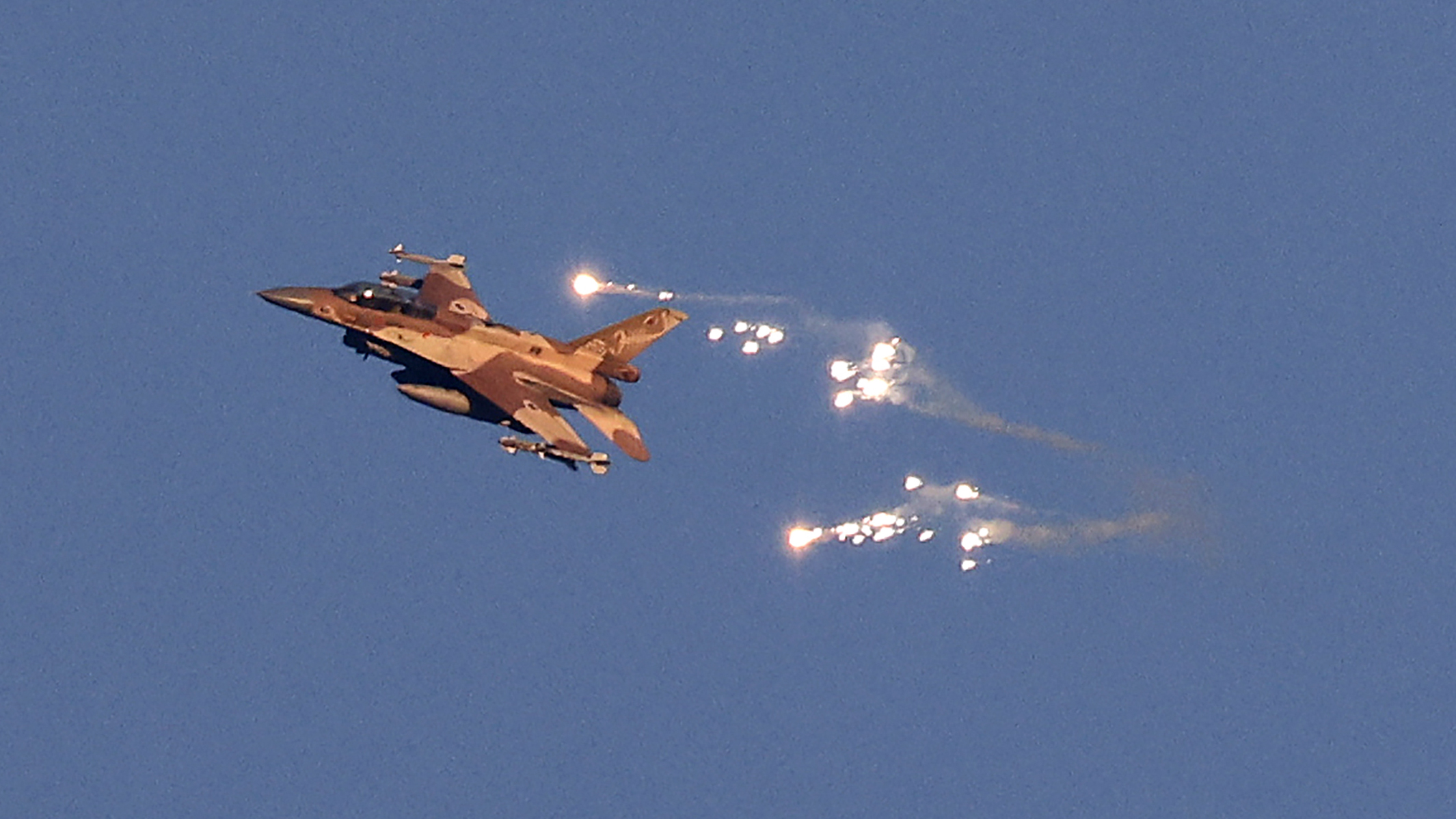 This photo taken from a position in northern Israel shows an Israeli Air Force fighter jet firing flares as it flies to intercept a hostile aircraft that launched from Lebanon over the border area with south Lebanon on August 25, 2024. The Israeli military announced early August 25, 2024 that it was conducting pre-emptive strikes in Lebanon after detecting preparations for "large-scale" attacks by the Iran-backed militant group Hezbollah. Hezbollah said August 25, 2024 it had launched more than 320 rockets at Israel overnight, targeting a string of military positions, even as Israel's military said it was carrying out pre-emptive strikes against the group. (Photo by Jalaa MAREY / AFP) (Photo by JALAA MAREY/AFP via Getty Images)