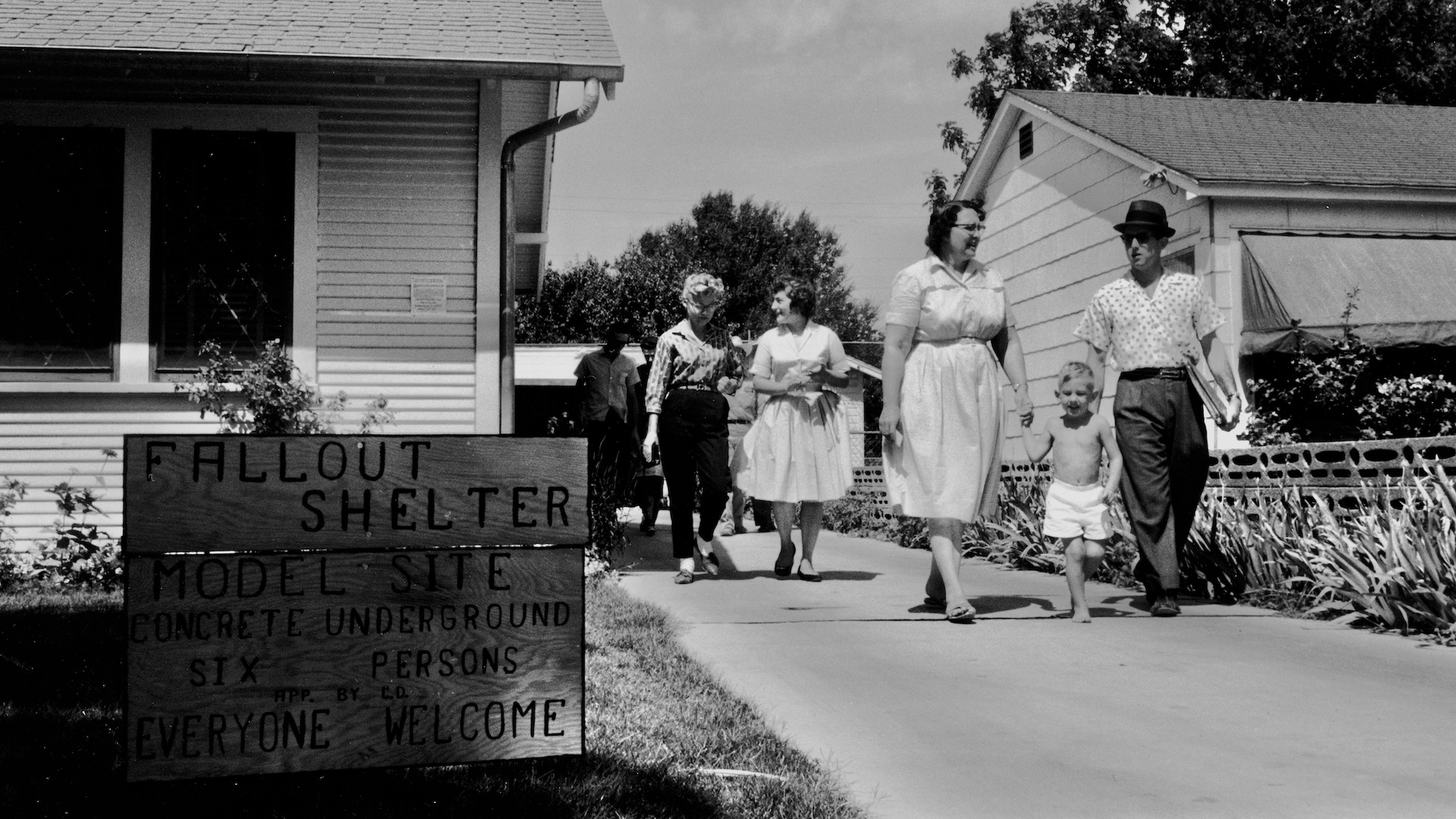 Families walk down the driveway while touring a model site home with a concrete basement fallout shelter, Texas, 1961. Photo by Shel Hershorn/Getty Images.