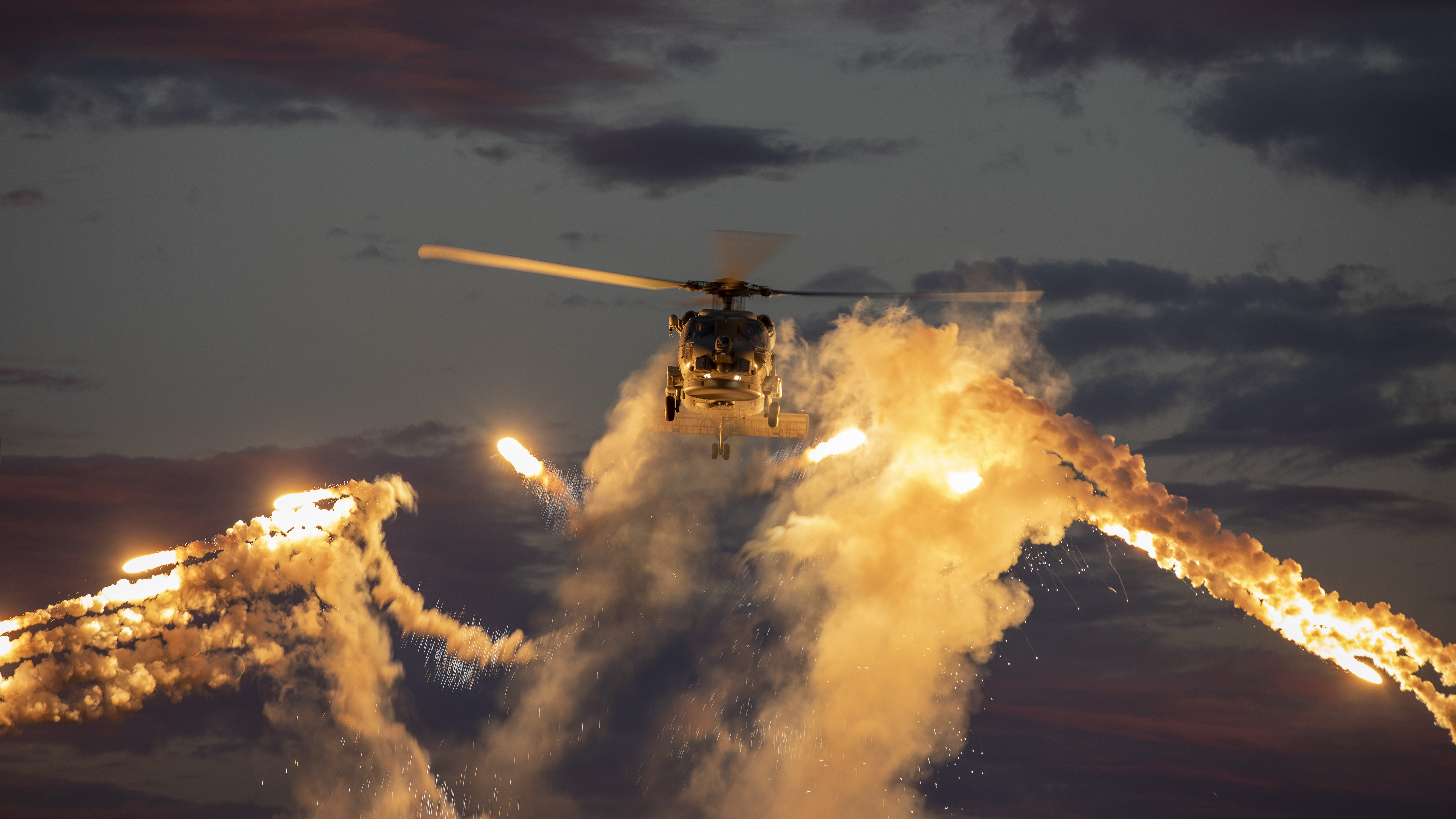 HMAS Hobart's embarked MH-60R Seahawk helicopter fires flares off the coast of New South Wales. This image has been digitally altered. *** Local Caption *** The Royal Australian Navy is conducting a regional deployment across Southeast Asia from July to October 2020 with HMA Ships Hobart, Stuart, Arunta and Sirius. The deployment demonstrates Australia's enduring commitment to the security and stability of the Indo-Pacific and to sustaining strong and positive defence relationships with regional nations. All parts of the deployment are being conducted in accordance with COVID-19 safety measures.