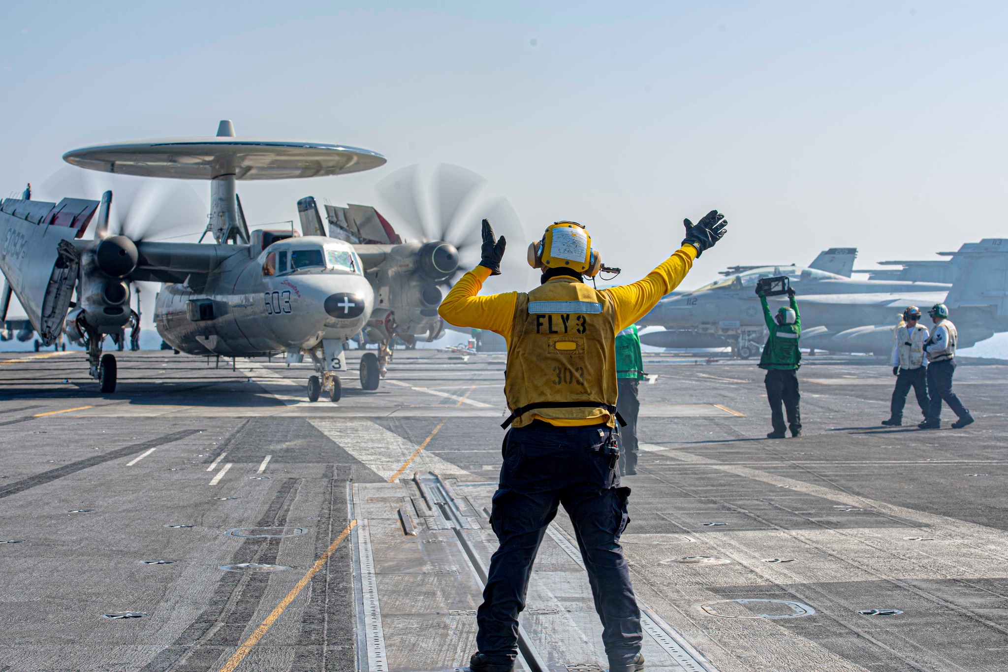 231105-N-JC256-1168 RED SEA (Nov. 5, 2023) - U.S. Navy Aviation Boatswain's Mate (Handling) 2nd Class Brandon Frayde guides an E-2C Hawkeye, attached to the "Screwtops" of Airborne Command and Control Squadron (VAW) 123, to launch during flight operations aboard the aircraft carrier USS Dwight D. Eisenhower (CVN 69) in the Red Sea, Nov. 5, 2023. The Eisenhower Carrier Strike Group is deployed to the U.S. 5th Fleet area of operations to support maritime security and stability in the Middle East region. (U.S.