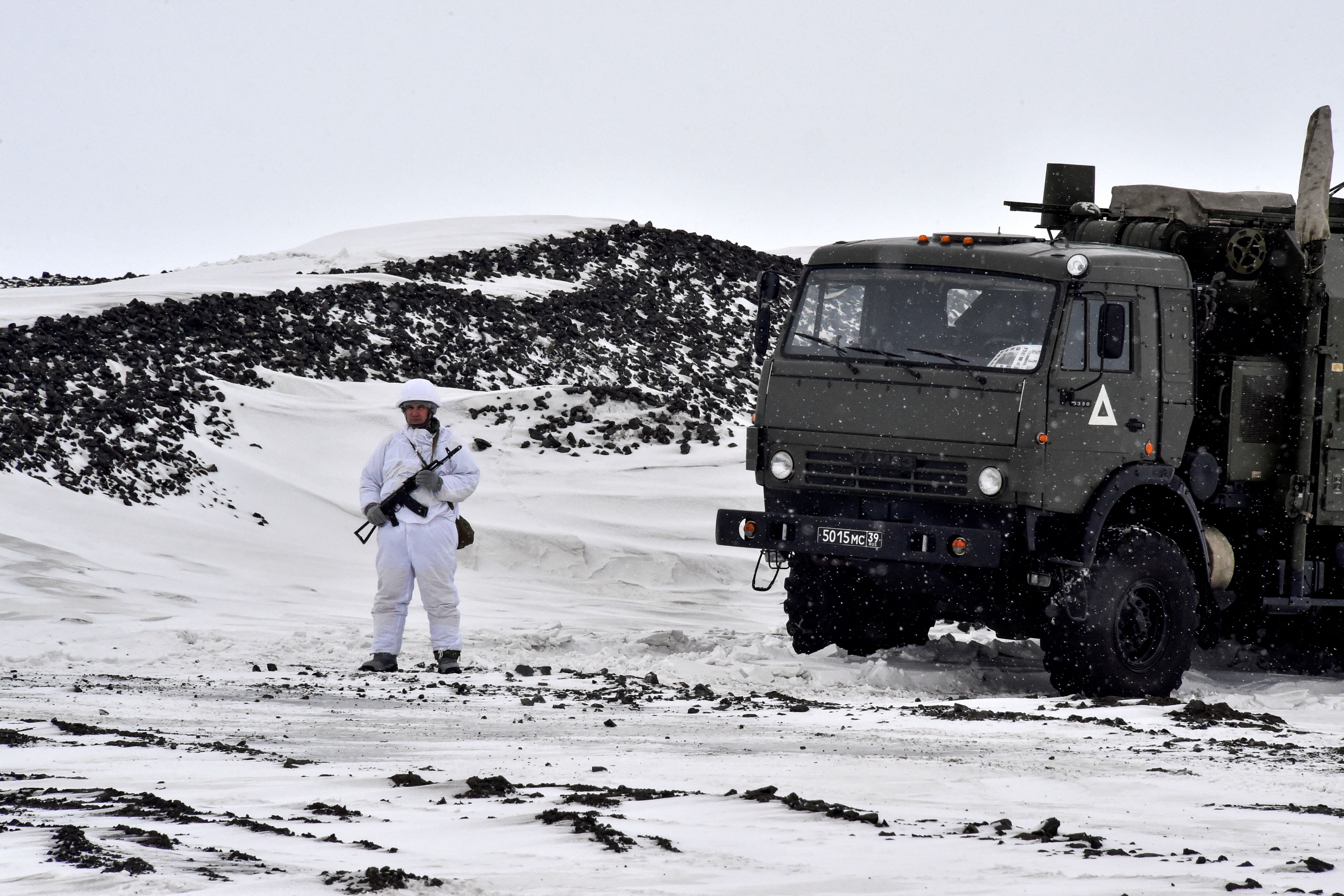 TOPSHOT - A Russian serviceman stands guard by a military truck on the island of Alexandra Land, which is part of the Franz Josef Land archipelago, on May 17, 2021. (Photo by Maxime POPOV / AFP) (Photo by MAXIME POPOV/AFP via Getty Images)