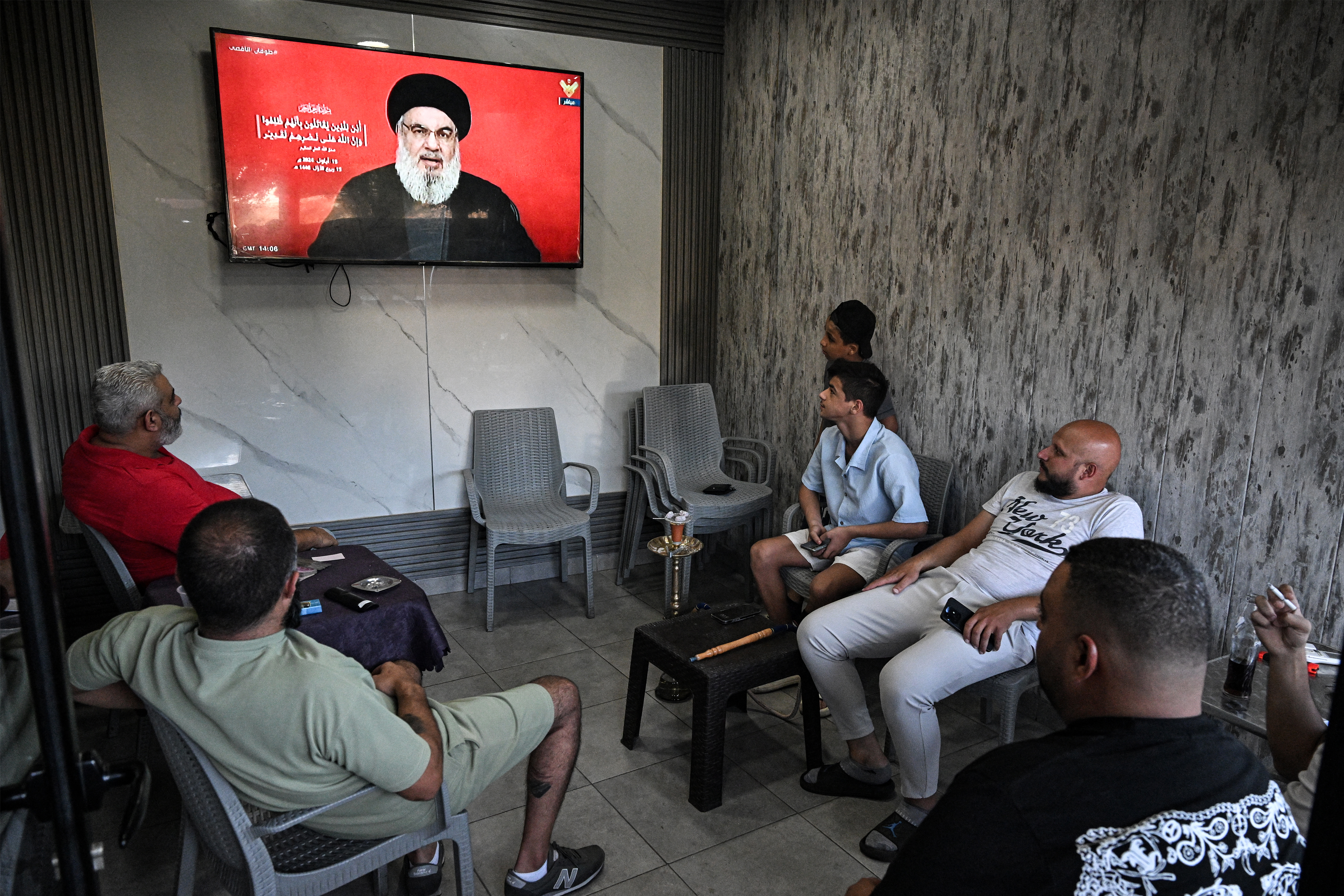 People attend a televised speech by the leader of the Lebanese Shiite movement Hezbollah Hassan Nasrallah from a cafe at the entrance of the Sabra camp for Palestinian refugees in Beirut's southern suburb on September 19, 2024. Lebanon's powerful Hezbollah chief said on September 19 that Israel will not be able to return residents of the north displaced by 11 months of cross-border exchanges to their homes through military escalation. (Photo by JOSEPH EID / AFP) (Photo by JOSEPH EID/AFP via Getty Images)