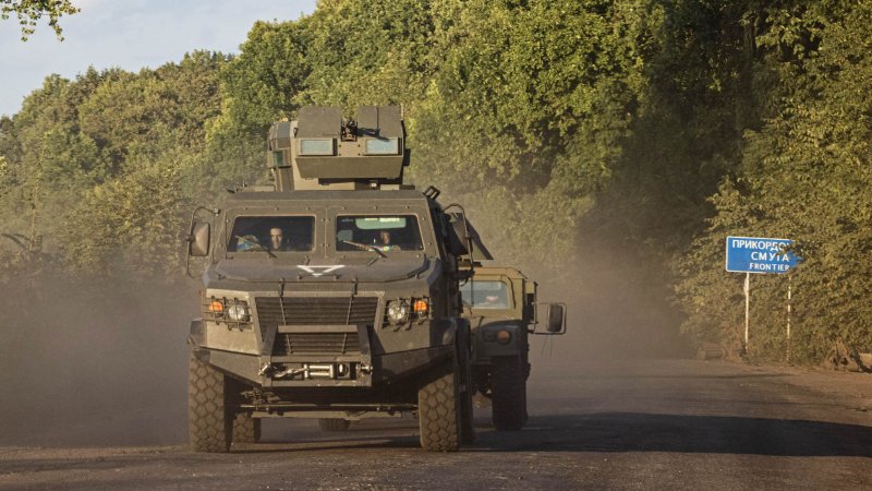 Military vehicles drive down a road past a sign indicating that the border to Russia is approaching north of Sumy on August 15th 2024, in Sumy Region, Ukraine. Ukraines's incursion into Russia's Kursk has continued into a second week.