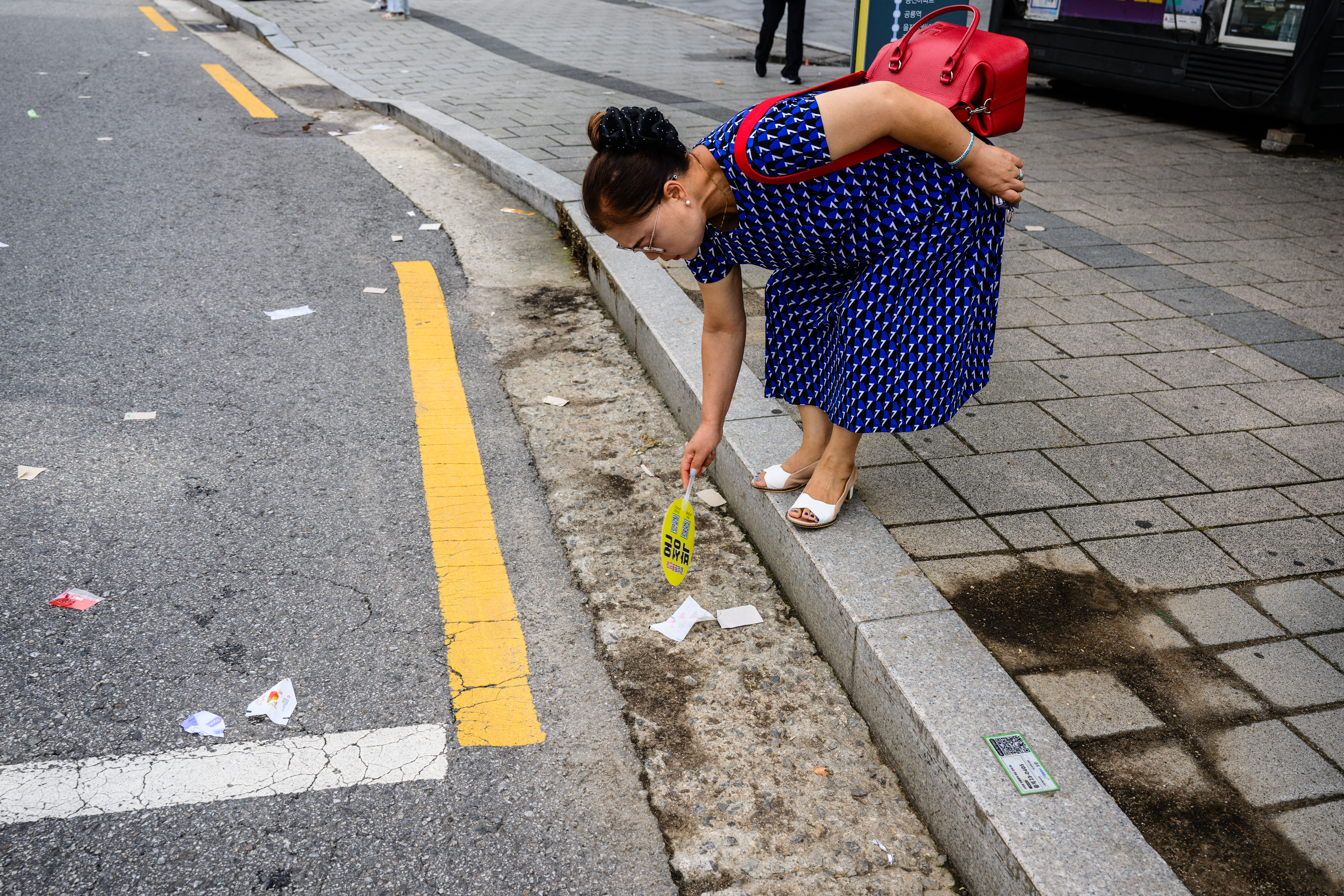 A pedestrian uses a fan to inspect sweet wrappers suspected to be from trash balloons sent from North Korea, in Seoul on July 24, 2024. North Korean sweet wrappers and packets of crackers and other snacks made at a factory once visited by leader Kim Jong Un were found by AFP reporters on Seoul streets on July 24. (Photo by Anthony WALLACE / AFP) (Photo by ANTHONY WALLACE/AFP via Getty Images)