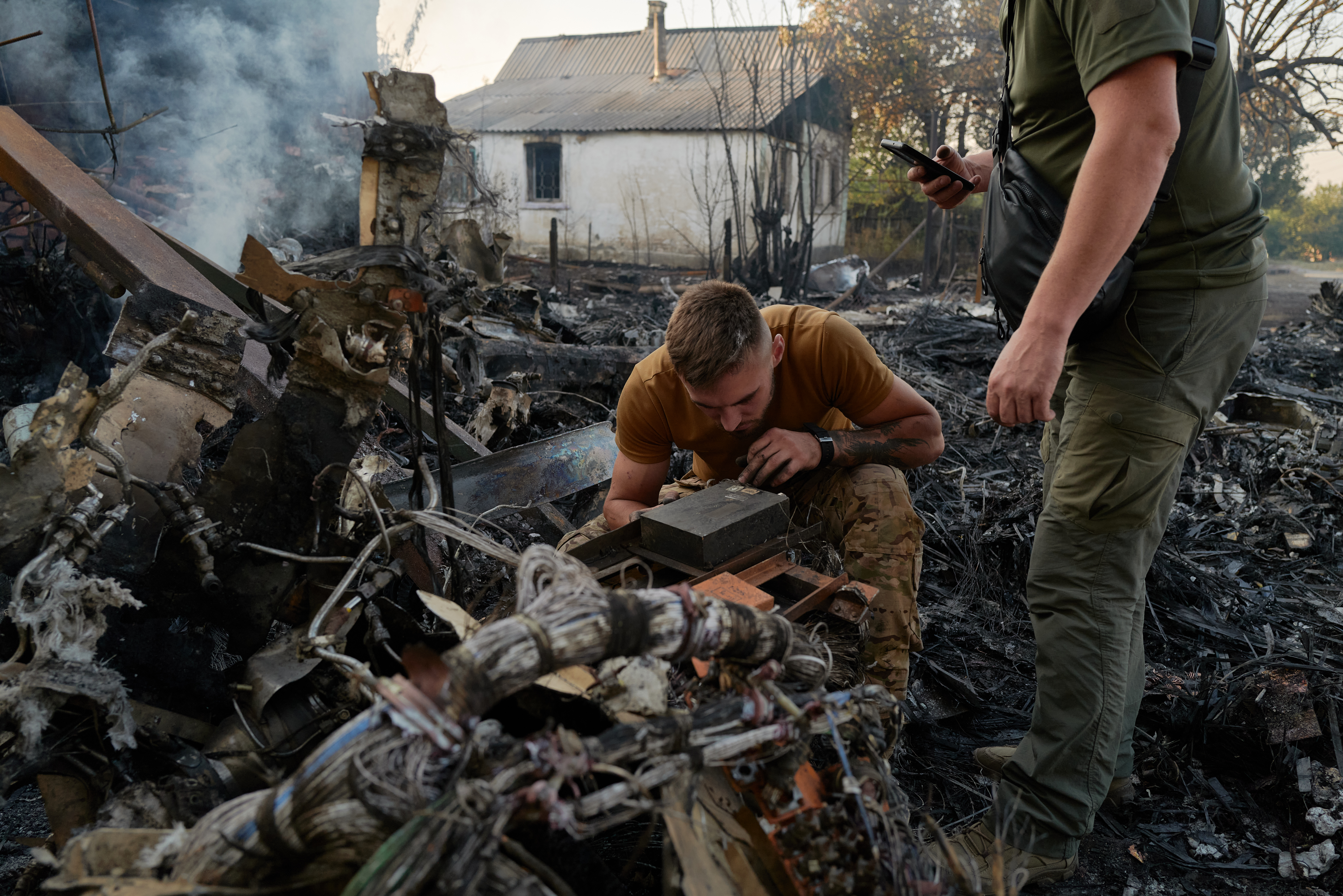 KOSTYANTYNIVKA, UKRAINE – OCTOBER 5: Ukrainian soldiers examine the wreckage of a crashed Russian aircraft, likely a Sukhoi S-70 "Stealth" Heavy unmanned combat aircraft (UCAV) that crashed in a residential area and set a house on fire in Kostiantynivka, Ukraine, on October 5, 2024. (Photo by Pierre Crom/Getty Images)