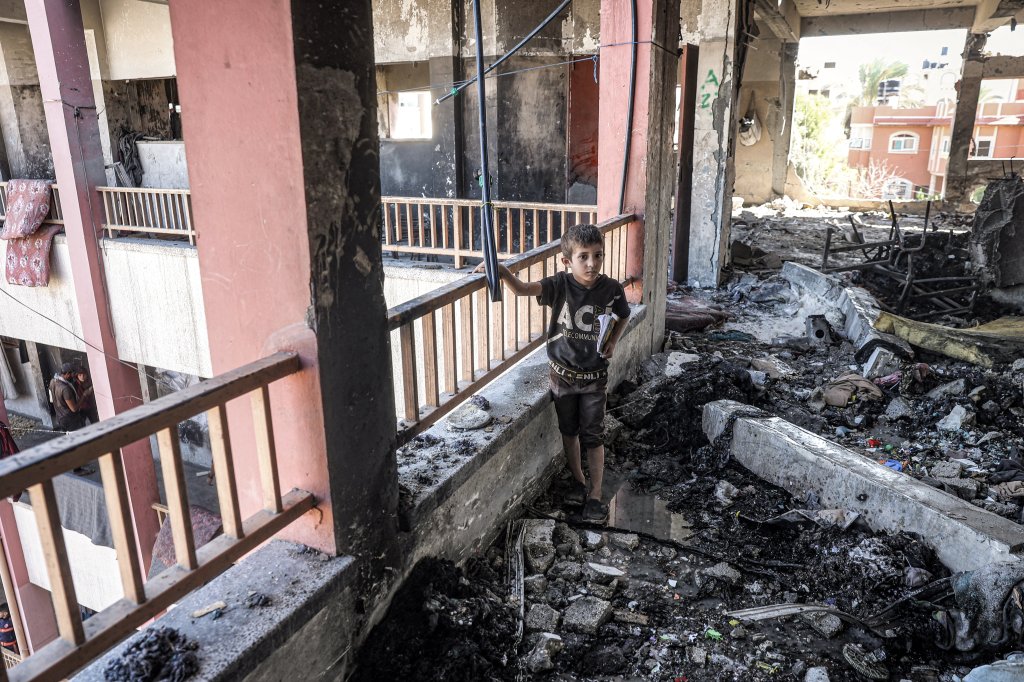 A boy walks with a notebook through debris and rubble in the balcony corridor of the Shuhada (Martyrs) school, which was hit by Israeli bombardment, in Nuseirat in the central Gaza Strip on October 24, 2024 amid the ongoing war in the Palestinian territory between Israel and Hamas. (Photo by Eyad BABA / AFP) (Photo by EYAD BABA/AFP via Getty Images)