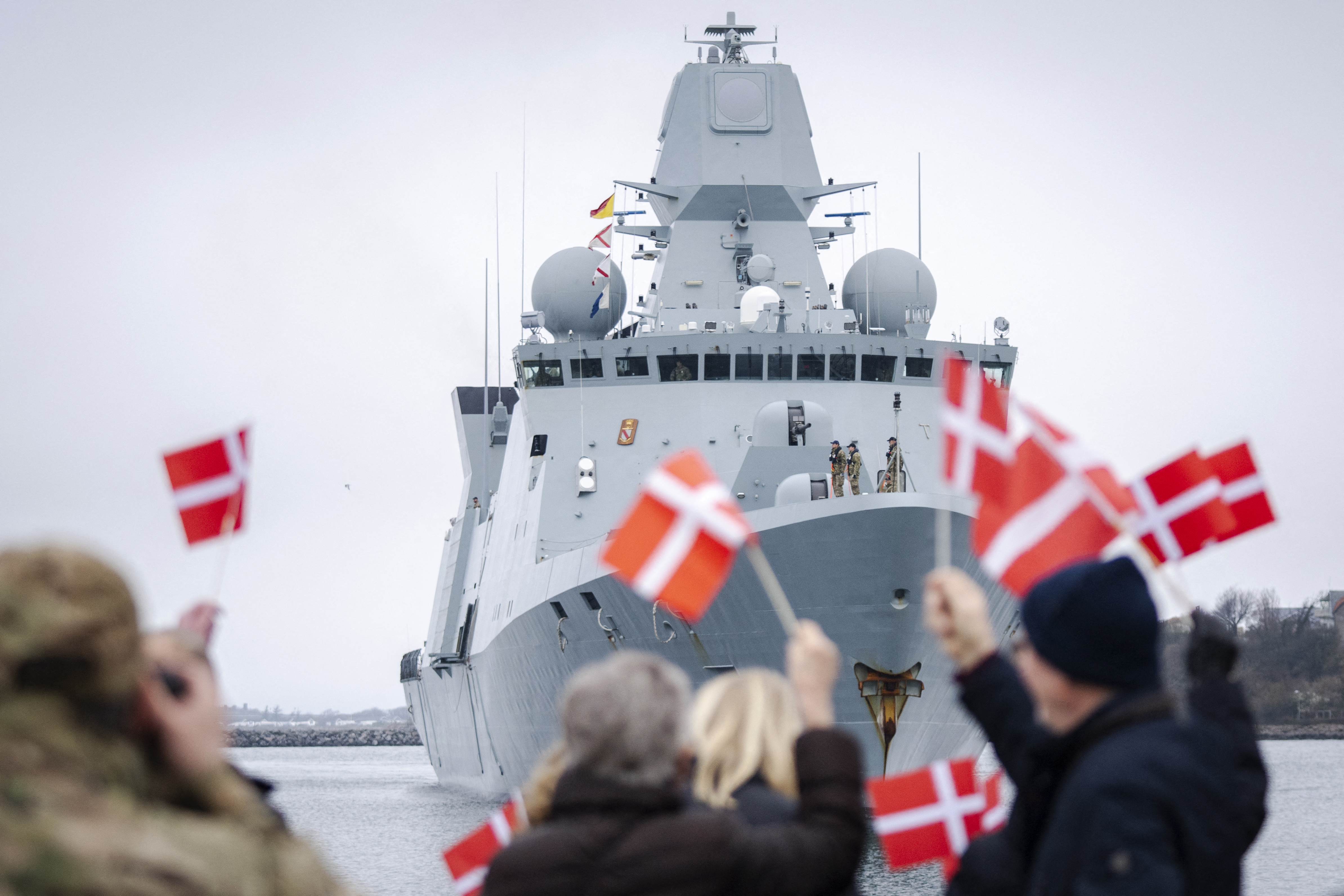 Relatives of crew members wave with Danish flags as the frigate HDMS Iver Huitfeldt (F361) of the Royal Danish Navy arrives at the Naval Base in Korsoer, Denmark on April 4, 2024. Since February 2024, the Danish frigate Iver Huitfeldt has been deployed in the Red Sea as part of the US-led international naval coalition 'Operation Prosperity Guardian'. The coalition's task is to protect civilian shipping against attacks from the Houthi movement in Yemen. (Photo by Ida Marie Odgaard / Ritzau Scanpix / AFP) / Denmark OUT (Photo by IDA MARIE ODGAARD/Ritzau Scanpix/AFP via Getty Images)