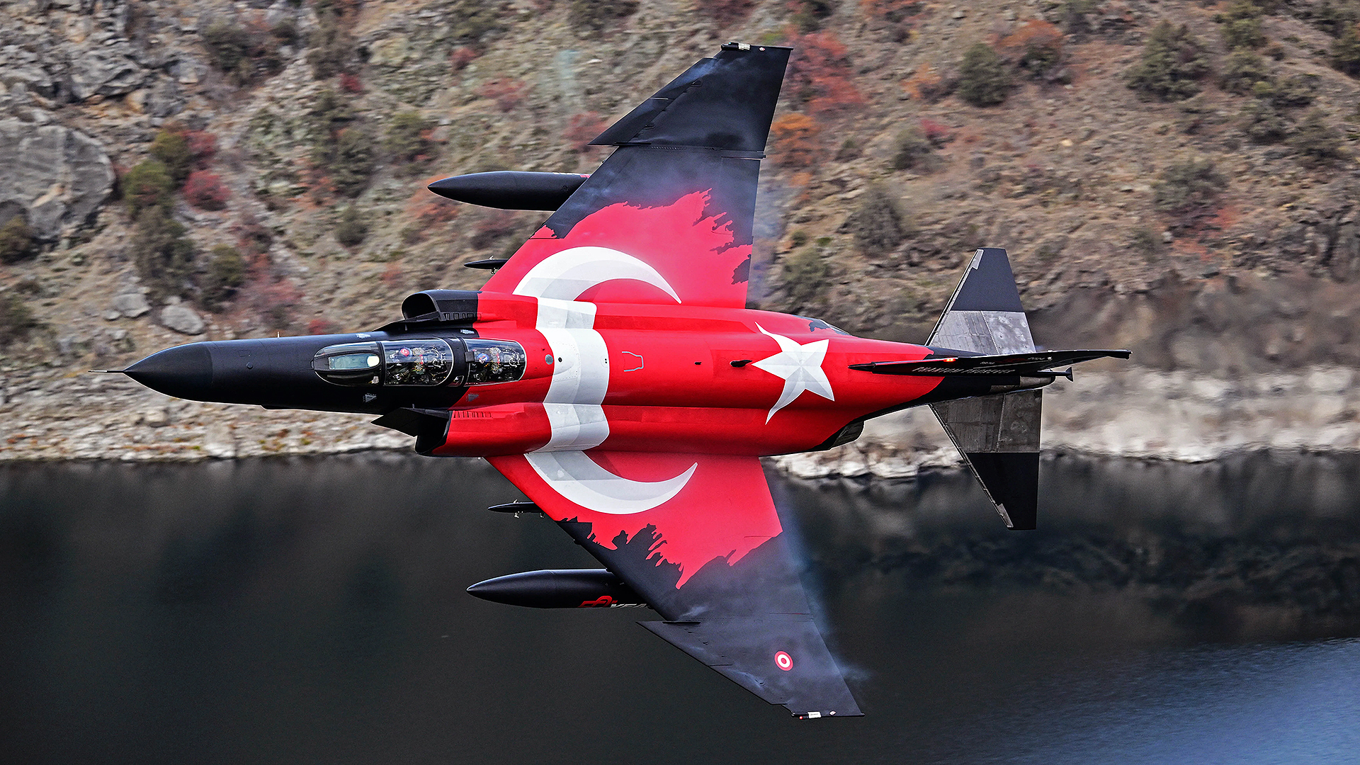 A Turkish Air Force F-4E Phantom II, adorned with a striking Turkish flag livery, soars in a low-altitude maneuver over Eskisehir to commemorate 50 years of service in the Turkish Air Force in Eskisehir, Turkiye on November 16, 2024.