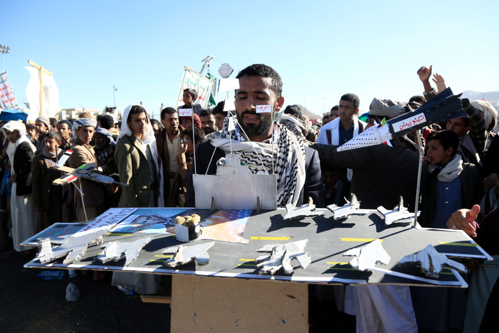 A supporter of Yemen's Iran-backed Houthi rebels fields a diorama of a U.S. warship under a Houthi missile during a demonstration in the capital Sanaa on Dec. 6, 2024.