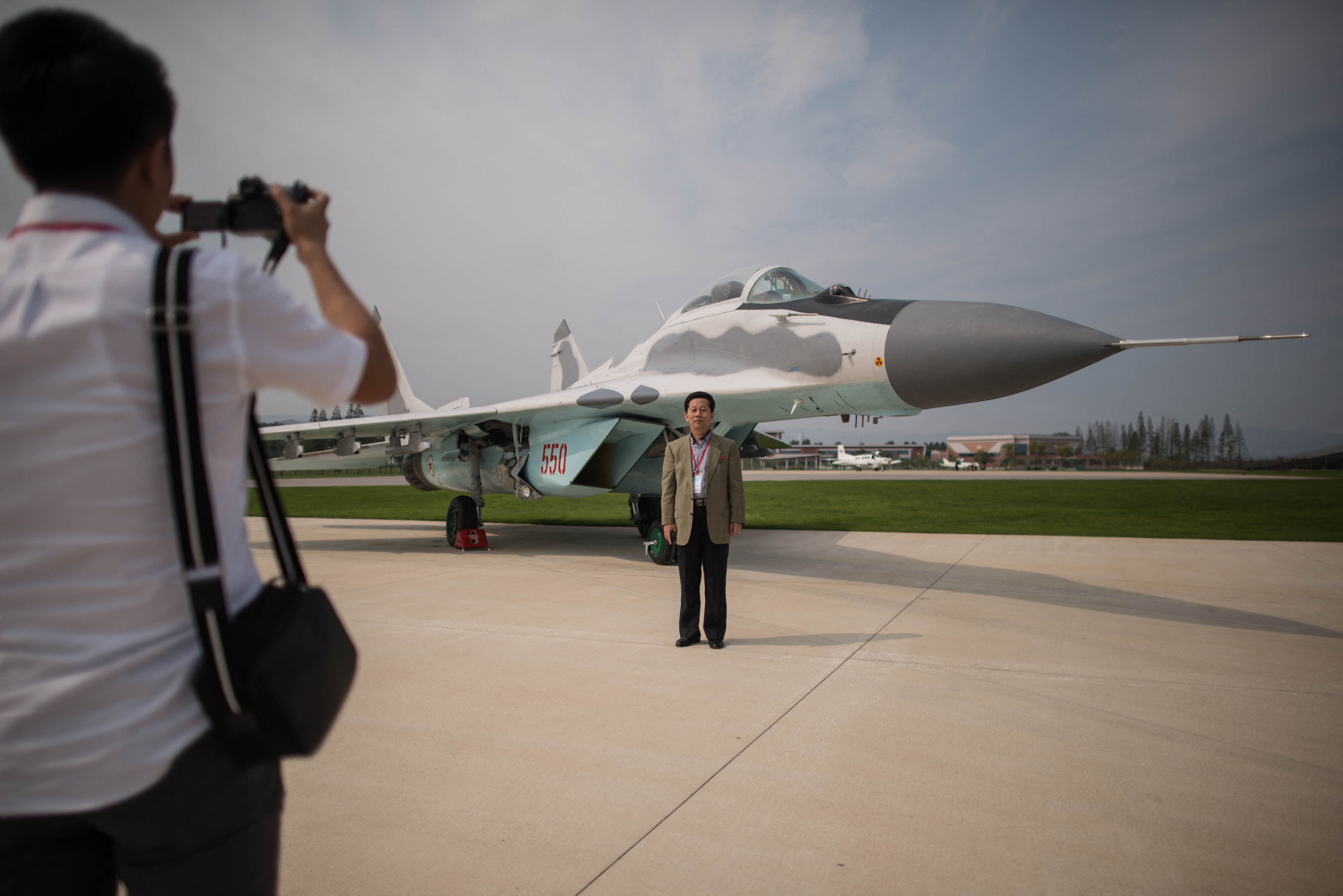 A spectator poses for photos before a MiG-29 aircraft during the second day of the Wonsan Friendship Air Festival in Wonsan on September 25, 2016. Just weeks after carrying out its fifth nuclear test, North Korea put on an unprecedented civilian and military air force display Saturday at the country's first ever public aviation show. (Photo by Ed Jones / AFP) (Photo by ED JONES/AFP via Getty Images)