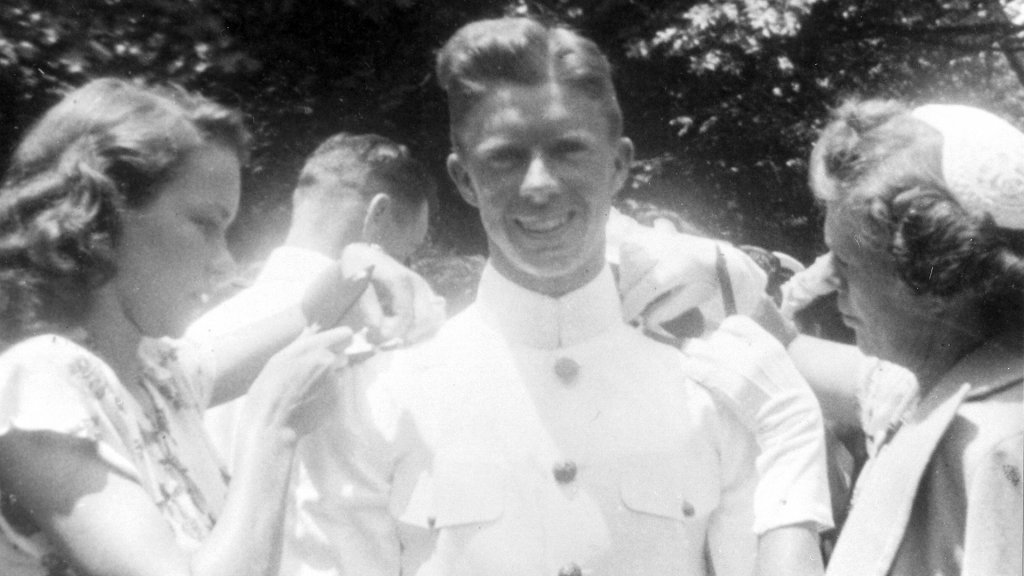 Former President Jimmy Carter becomes an ensign upon graduating from the U.S. Naval Academy, Annapolis, MD in 1946. His wife, Rosalynn Carter (Left) and mother, Bessie Cater, attaches is rank badges onto his uniform. Photo courtesy of Jimmy Carter Library and Museum.