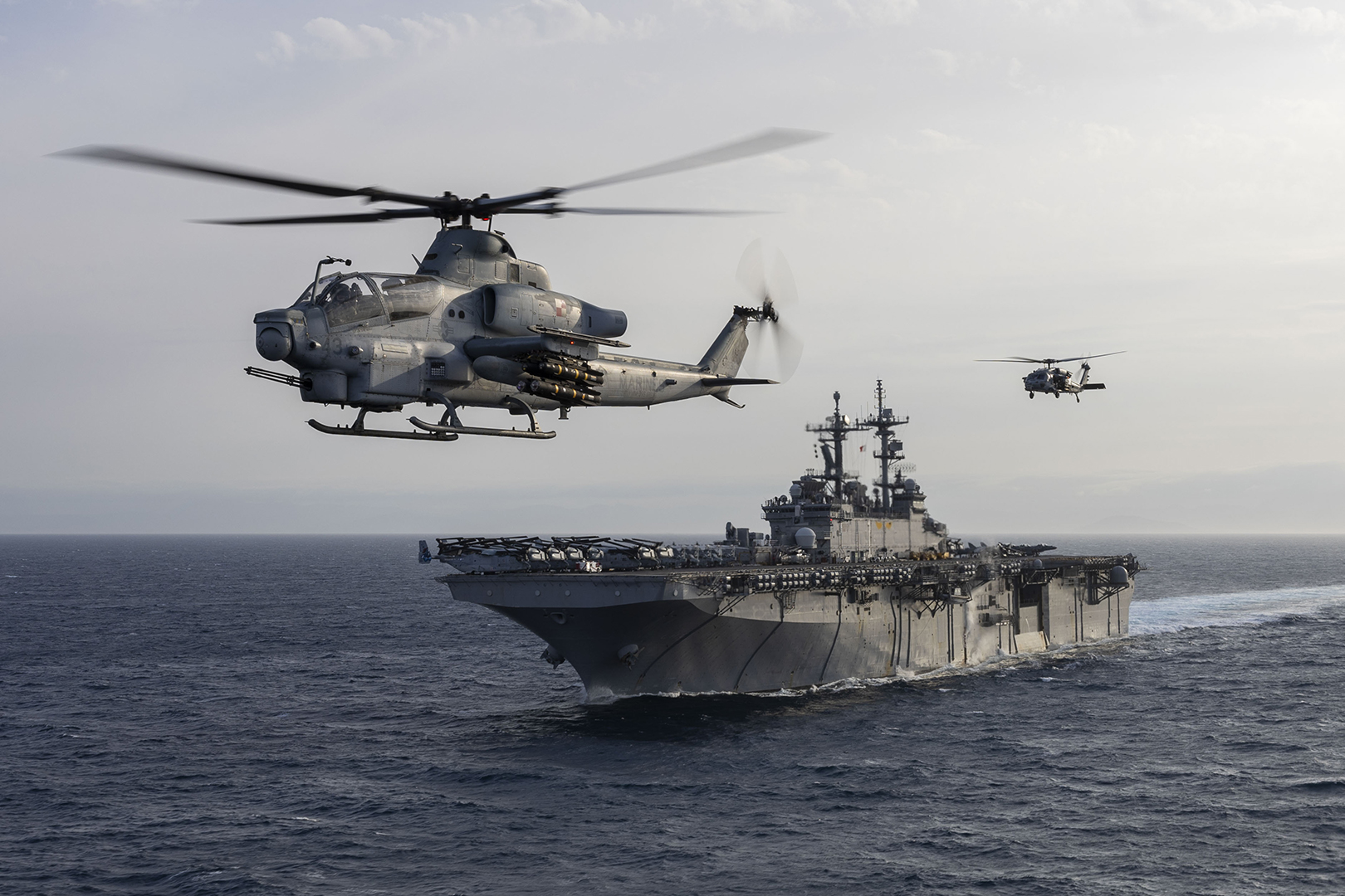 STRAIT OF GIBRALTAR (June, 26, 2024) An AH-1Z Viper, left, assigned to the “Blue Knights” of Marine Medium Tiltrotor Squadron (VMM) 365 (Reinforced), and an MH-60S Sea Hawk, assigned to the “Dragon Whales” of Helicopter Sea Combat Squadron (HSC) 28, flies patrol as the amphibious assault ship USS Wasp (LHD 1) transits the Strait of Gibraltar, June 26, 2024. Wasp is conducting operations in the U.S. Naval Forces Europe area of operations as the flagship of the Wasp Amphibious Ready Group (WSP ARG)-24th Marine Expeditionary Unit (MEU) Special Operations Capable (SOC). The WSP ARG-24th MEU (SOC) supports high-end warfighting exercises while demonstrating speed and agility operating in a dynamic security environment. (U.S. Navy photo by Mass Communication Specialist 2nd Class Sydney Milligan)