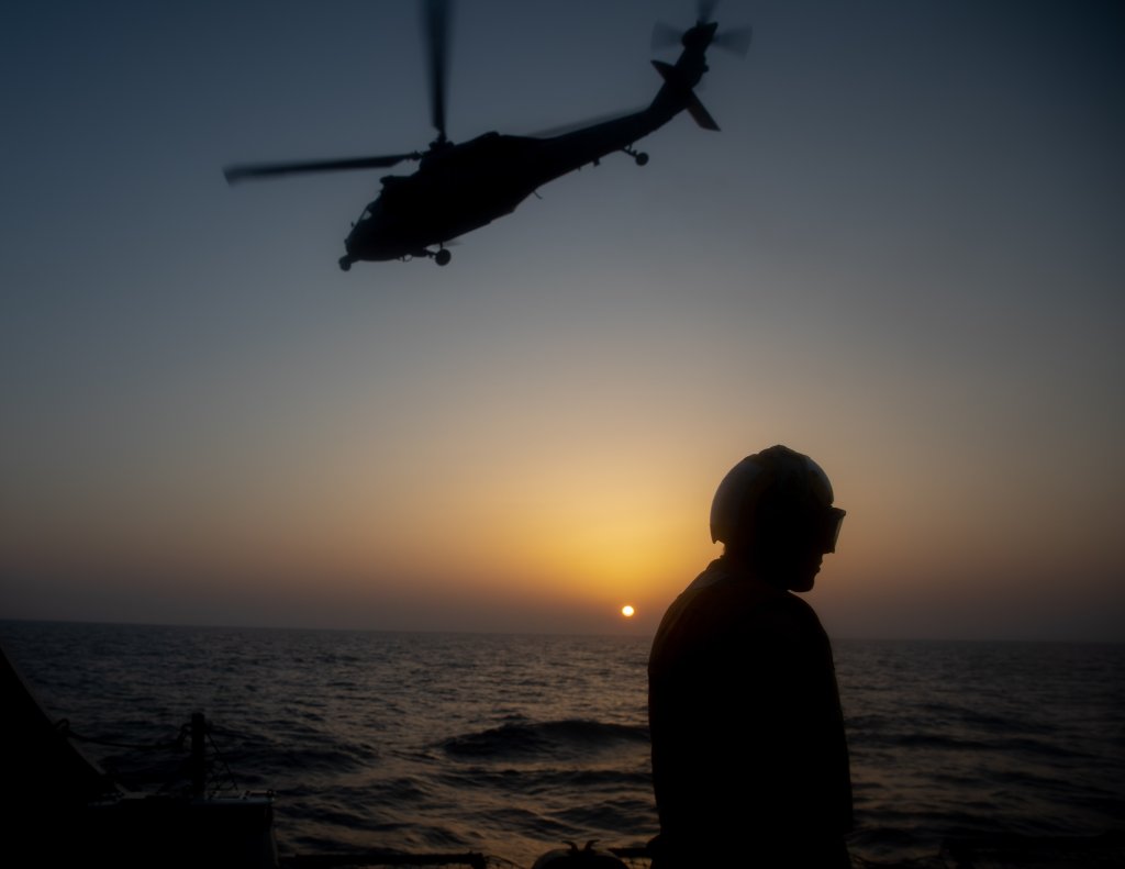 240313-N-BT677-1005 GULF OF ADEN (March 13, 2024) A Boatswain's Mate walks the flight deck as an MH-60S Sea Hawk helicopter, attached to the "Dusty Dogs" of Helicopter Sea Combat (HSC) 7, takes off from the Arleigh Burke-class guided-missile destroyer USS Gravely (DDG 107) during flight quarters in the Gulf of Aden, March 13. Gravely is deployed to the U.S. 5th Fleet area of operations to support maritime security and stability in the Middle East. (Official U.S. Navy photo)