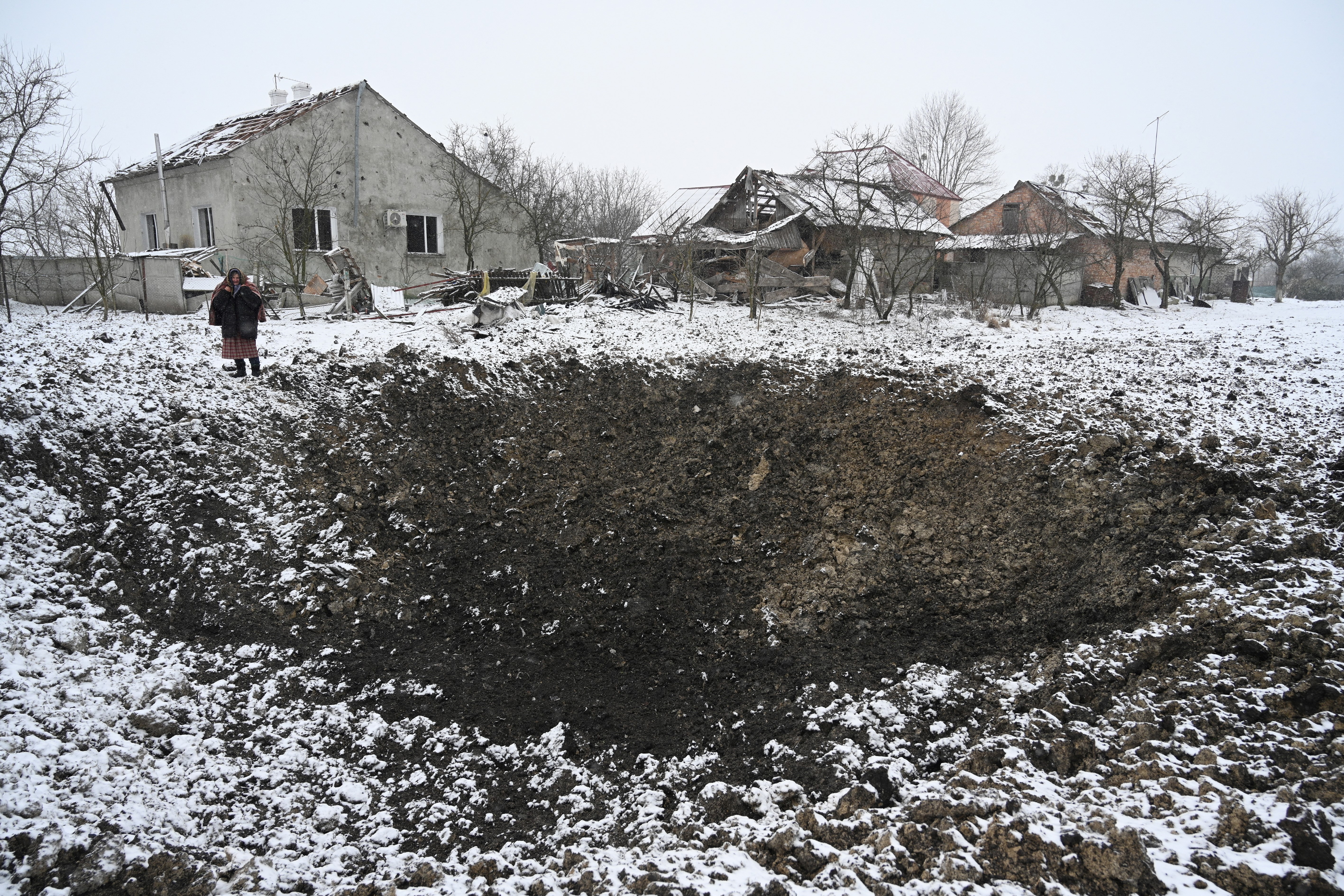 TOPSHOT - Yaroslava Sukach, 77, a local resident whose house was destroyed stands next to a crater following a missile strike on the village of Sknyliv, some 60km from Lviv, on January 15, 2025, amid the Russian invasion of Ukraine. Russia launched dozens of missiles and drones at the Ukrainian energy sector, Kyiv said on January 15, ramping up a months-long bombing campaign at a precarious moment of the war for Ukraine. The Ukrainian air force said Russia had deployed 43 cruise and ballistic missiles and 74 attack drones in the overnight barrage that appeared to have targeted sites mainly in western Ukraine. (Photo by YURIY DYACHYSHYN / AFP) (Photo by YURIY DYACHYSHYN/AFP via Getty Images)