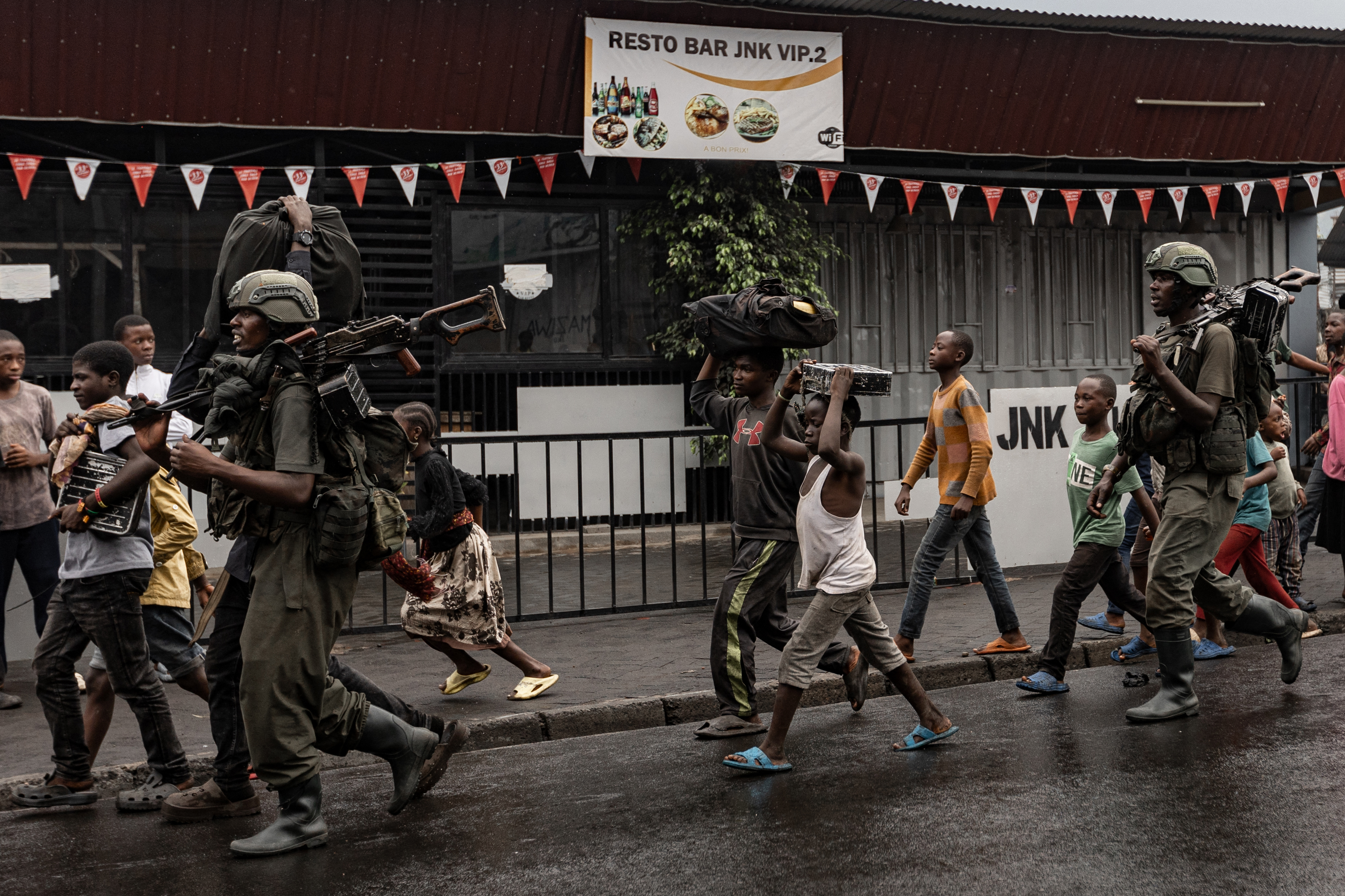 TOPSHOT - Members of the M23 armed group walk alongside residents through a street of the Keshero neighborhood in Goma, on January 27, 2025. The besieged Congolese city of Goma was rocked by heavy artillery fire on January 27, 2025 as France warned the regional capital was on the brink of falling to militia fighters and Rwandan troops. The M23 armed group and Rwandan soldiers entered Goma's centre on the night of January 26, 2025 after weeks of advancing on the main city in DR Congo's mineral-rich North Kivu province. (Photo by -STR / AFP) (Photo by -STR/AFP via Getty Images)