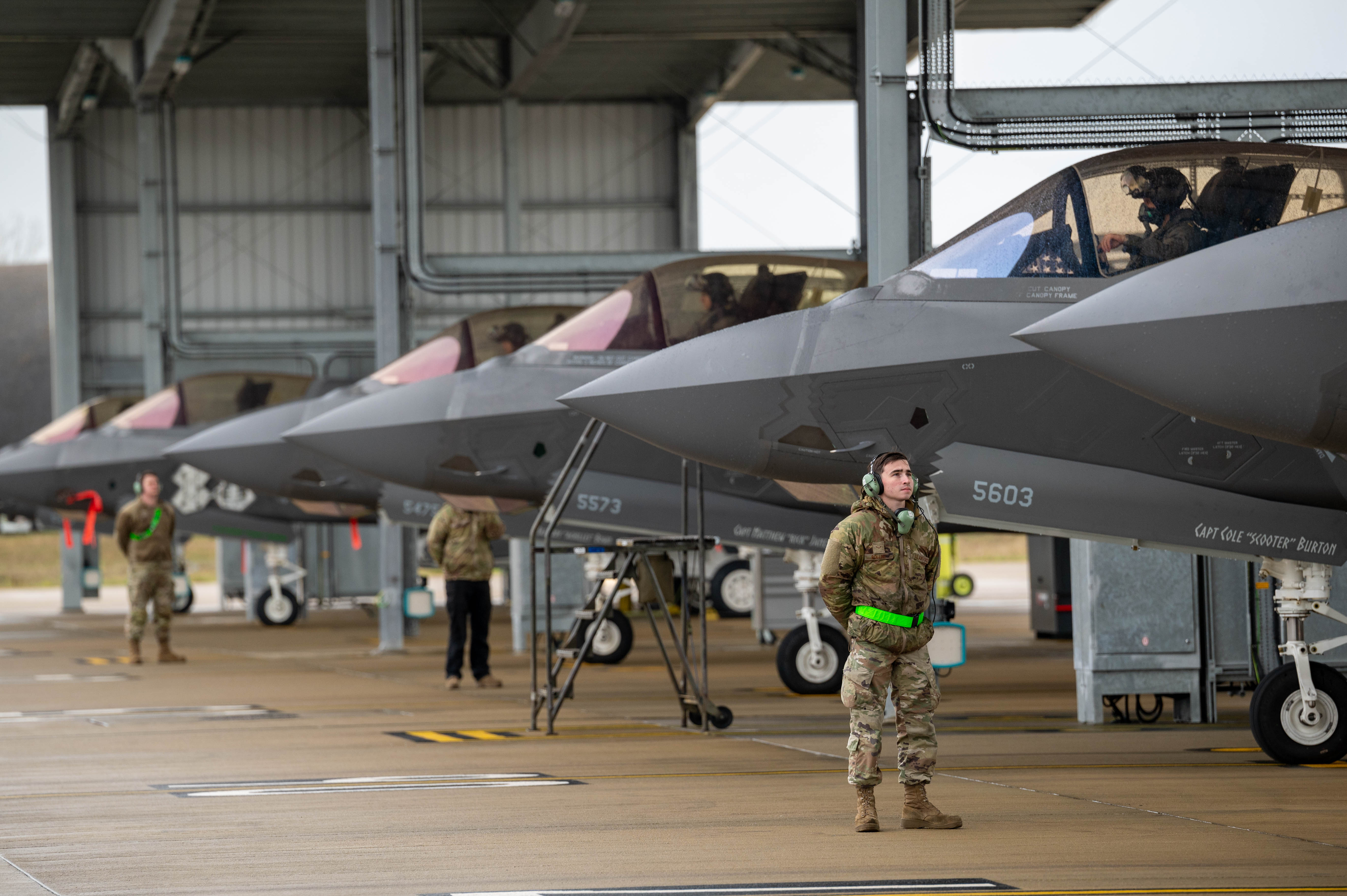 U.S. Air Force Airman 1st Class Wyatt Bolline, 495th Fighter Generation Squadron assistant dedicated crew chief, stands by in preparation to launch an F-35A Lightning II aircraft at RAF Lakenheath, England, Nov. 19, 2024. The 495th FGS is essential to generating daily sorties, enabling pilots to train and maintain readiness to respond quickly and effectively when called upon. (U.S. Air Force photo by Senior Airman Seleena Muhammad-Ali)