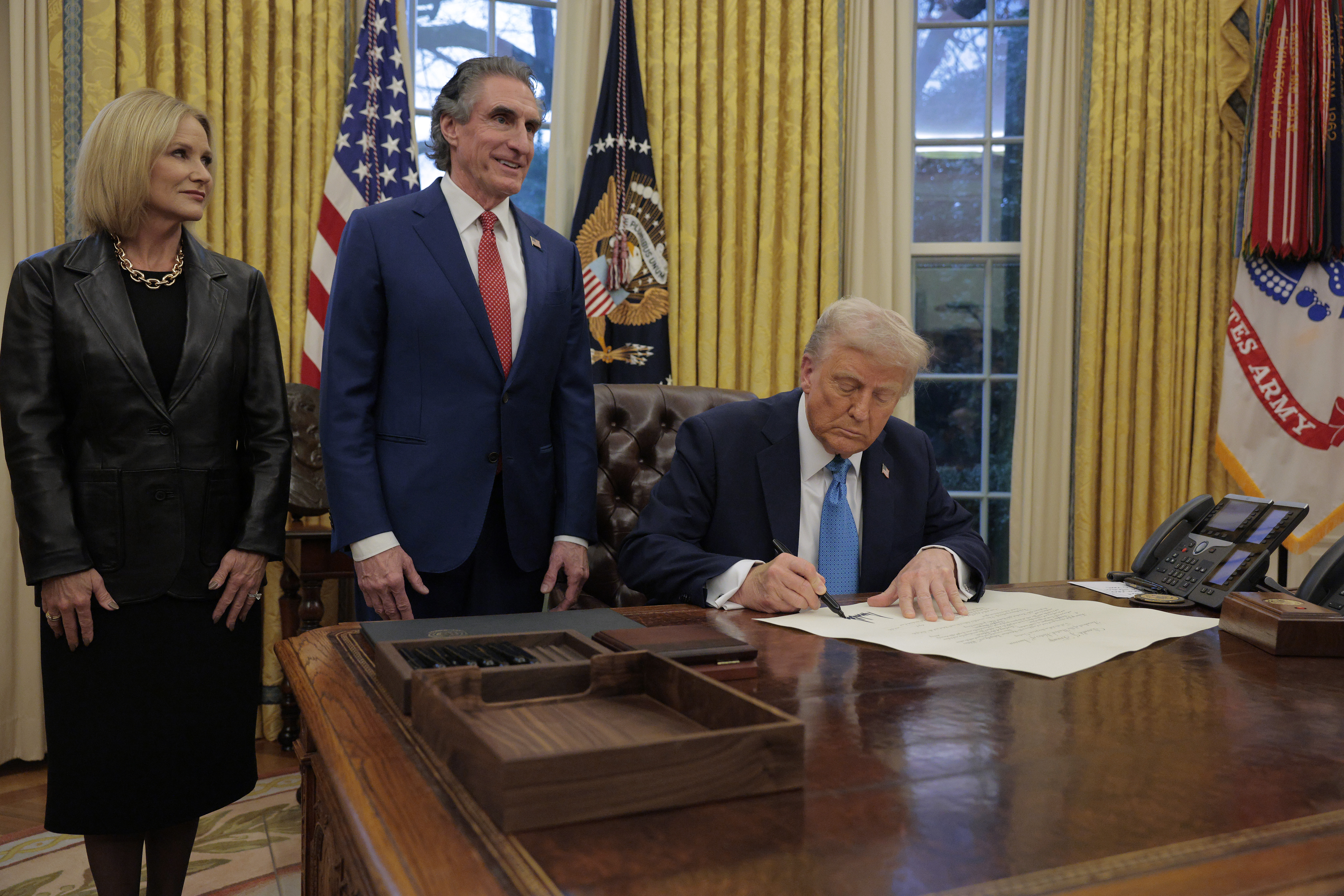 WASHINGTON, DC - JANUARY 31: U.S. President Donald Trump signs Interior Secretary Doug Burghum's commission with Burgum and his wife Kathryn Burgum in the Oval Office on January 31, 2025 in Washington, DC. Trump spoke to reporters about tariffs against China, Canada and Mexico and how Burghum will coordinate with the Energy Department and the Environmental Protection Agency. (Photo by Chip Somodevilla/Getty Images)