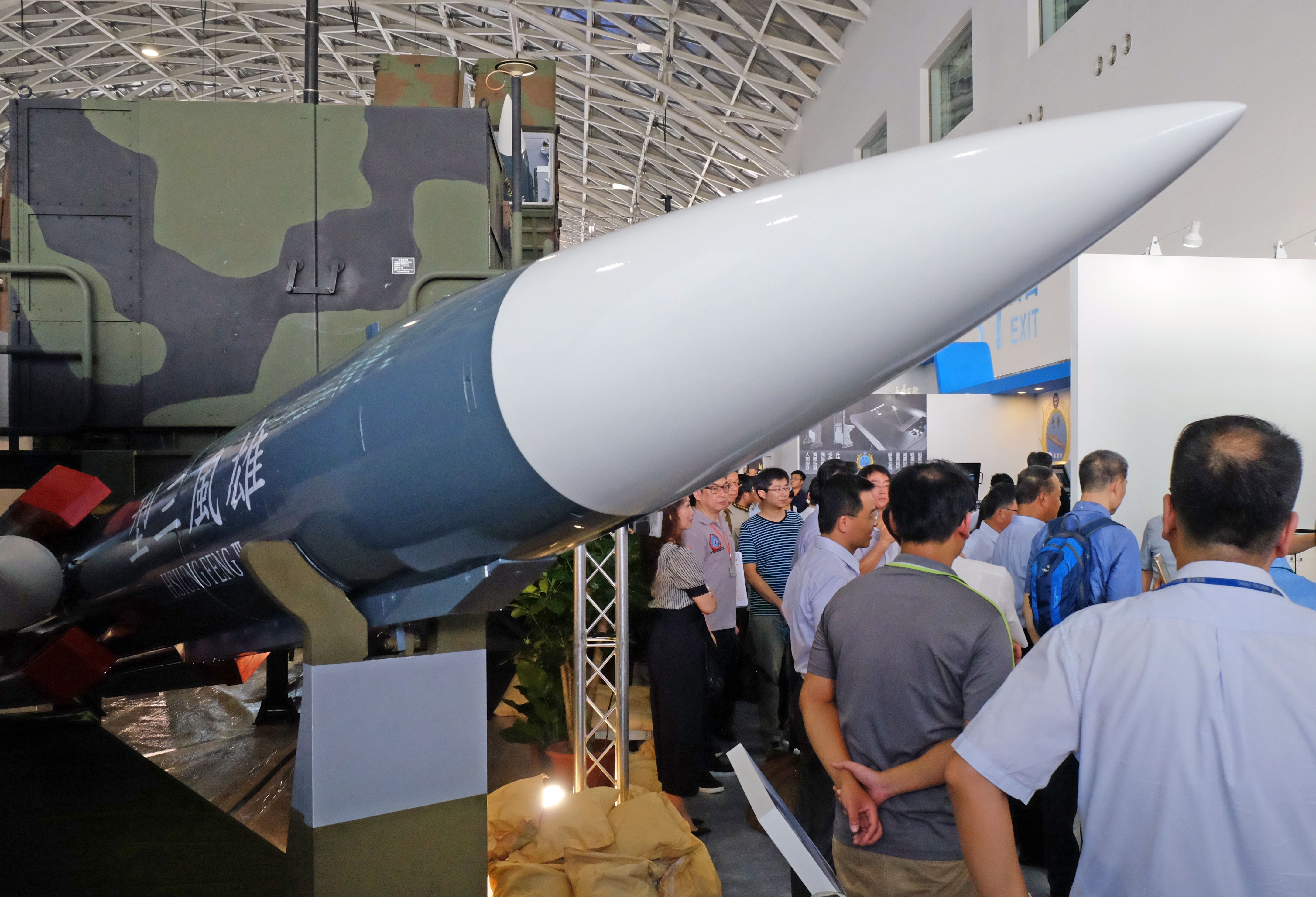 This photo taken on September 13, 2016 shows journalists listening next to a local made Hsiung Feng III missile model during the Kaohsiung International Marinetime and Defense Exhibition. More then 150 foreign and local component makers take part in this exhibition between September 16 to 19. / AFP / SAM YEH (Photo credit should read SAM YEH/AFP via Getty Images)