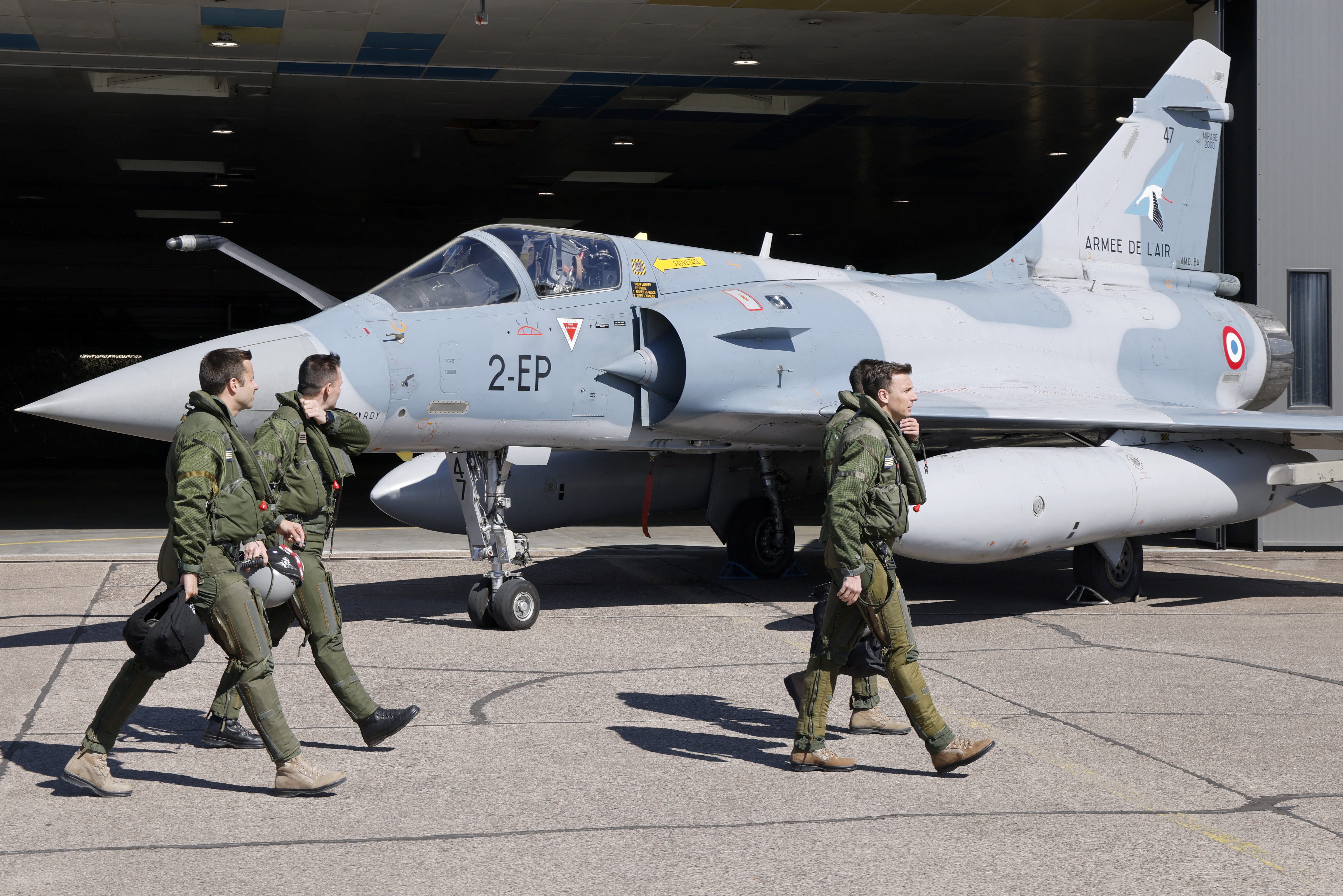 Members of the French Air and Space Force (Armée de l'air et de l'espace) walk past an aircraft on Luxeuil-Saint-Sauveur Airbase in Saint-Sauveur, north-eastern France on March 18, 2025, ahead of the visit of France's President Emmanuel Macron. (Photo by Ludovic MARIN / POOL / AFP) (Photo by LUDOVIC MARIN/POOL/AFP via Getty Images)