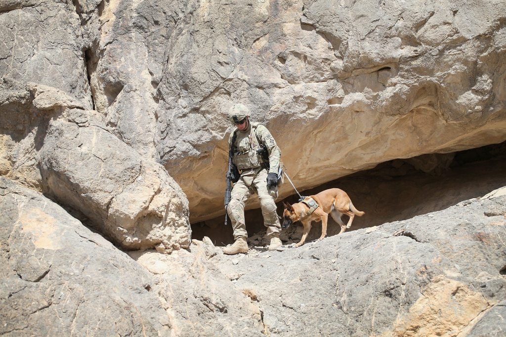 KANDAHAR, AFGHANISTAN - FEBRUARY 28: SPC Daniel Jackson from Centralia, Kansas and his dog Bailey with the 904th Military Police Detachment search through caves looking for weapons caches during a patrol with the U.S. Army's 4th squadron 2d Cavalry Regiment on February 28, 2014 near Kandahar, Afghanistan. Defense Secretary Chuck Hagel announced recently he is making preparations for a complete military withdrawal from Afghanistan because Afghanistan President Hamid Karzai continues to refuse to sign the Bilateral Security Agreement. Fourth squadron 2d Cavalry Regiment is responsible for defending Kandahar Airfield against rocket attacks from insurgents. (Photo by Scott Olson/Getty Images)