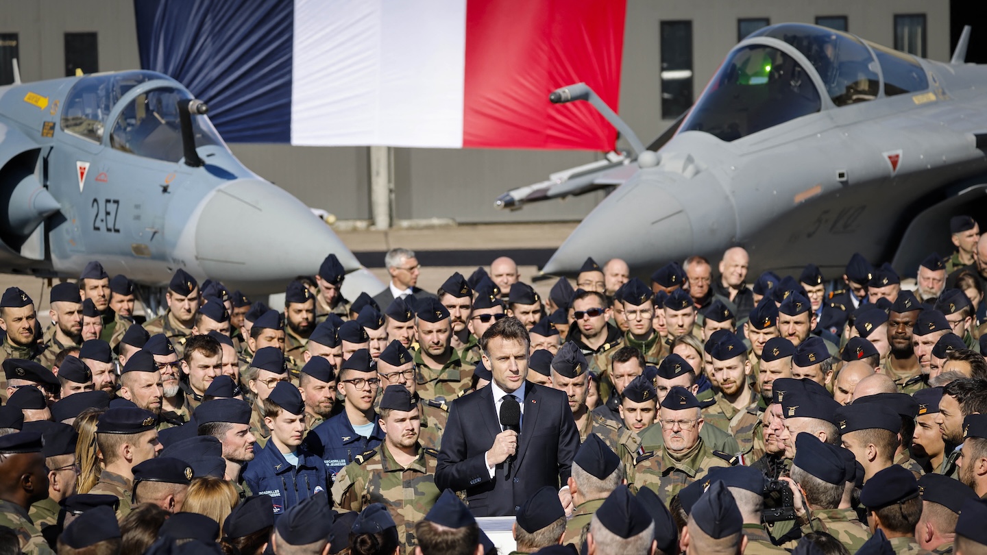 France's President Emmanuel Macron (C) delivers a speech in front of a Dassault Mirage 2000 (L) and a Dassault Rafale (R) fighter aircrafts during his visit of the French Air and Space Force (Armee de l'air et de l'espace) Luxeuil-Saint-Sauveur Airbase in Saint-Sauveur, north-eastern France on March 18, 2025.